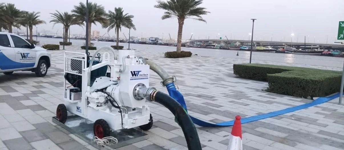 WellTech pump with discharge hose on a waterfront promenade